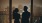 a man and woman standing next to each other and look out a window